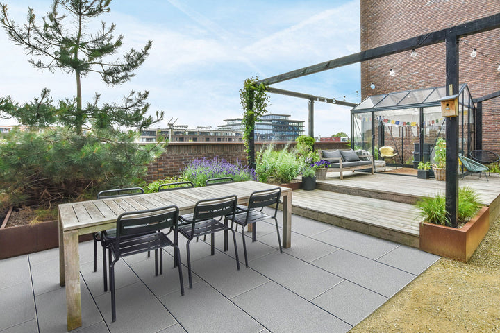60x40 LuxoGran-Terrassenplatten in grauer Natursteinoptik von Woehe & Heydemann verlegt auf einer modernen Dachterrasse  mit Gewächshaus und Lichterkette