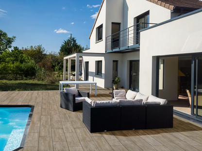 80x40 CeramicLine³-Terrassenplatten in brauner Natursteinoptik von Woehe & Heydemann verlegt auf einer modernen Terrasse mit Pool und Lounge