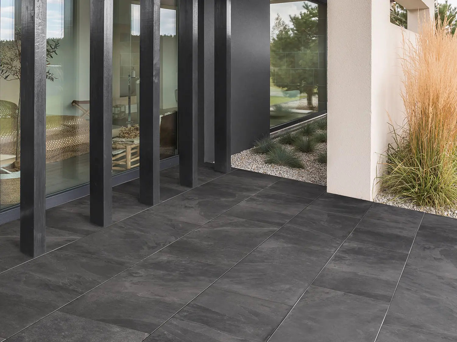 CeramicLine²-Terrassenplatten in grauer Natursteinoptik von Woehe & Heydemann verlegt auf einer Terrasse mit Pflanzen