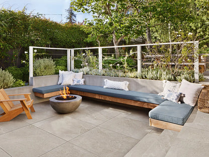 100x100 CeramicLine²-Terrassenplatten in beiger Natursteinoptik von Woehe & Heydemann verlegt auf einer modernen Terrasse mit Feuerstelle