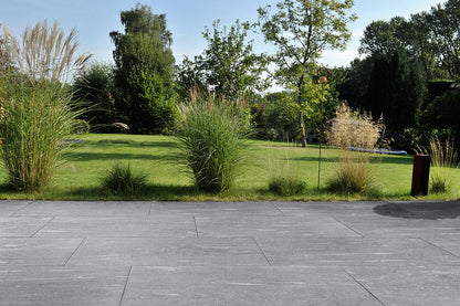 100x50 CeramicLine²-Terrassenplatten in grauer Natursteinoptik von Woehe & Heydemann verlegt auf einer modernen Terrasse mit Blick in den Garten