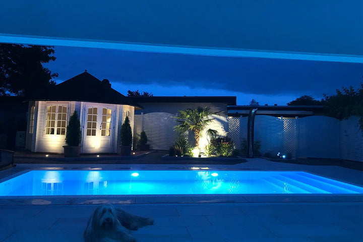 100x50 CeramicLine²-Terrassenplatten in beiger Natursteinoptik von Woehe & Heydemann verlegt auf einer modernen Terrasse mit Pool und Hund
