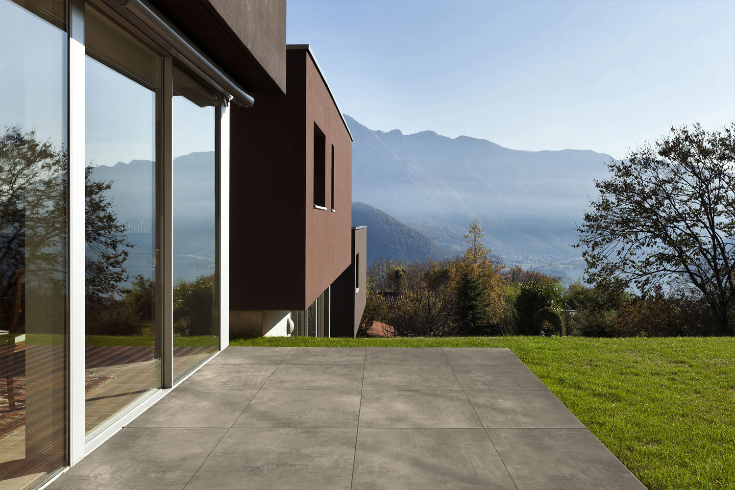 60x60 CeramicLine²-Terrassenplatten in beiger Betonoptik von Woehe & Heydemann verlegt auf einer modernen Terrasse mit Blick auf die Berge