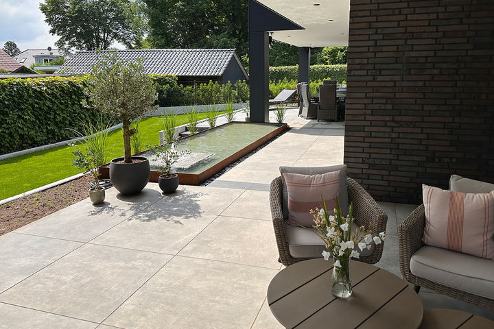 60x60 CeramicLine²-Terrassenplatten in beiger Natursteinoptik von Woehe & Heydemann verlegt auf einer modernen Terrasse im Garten