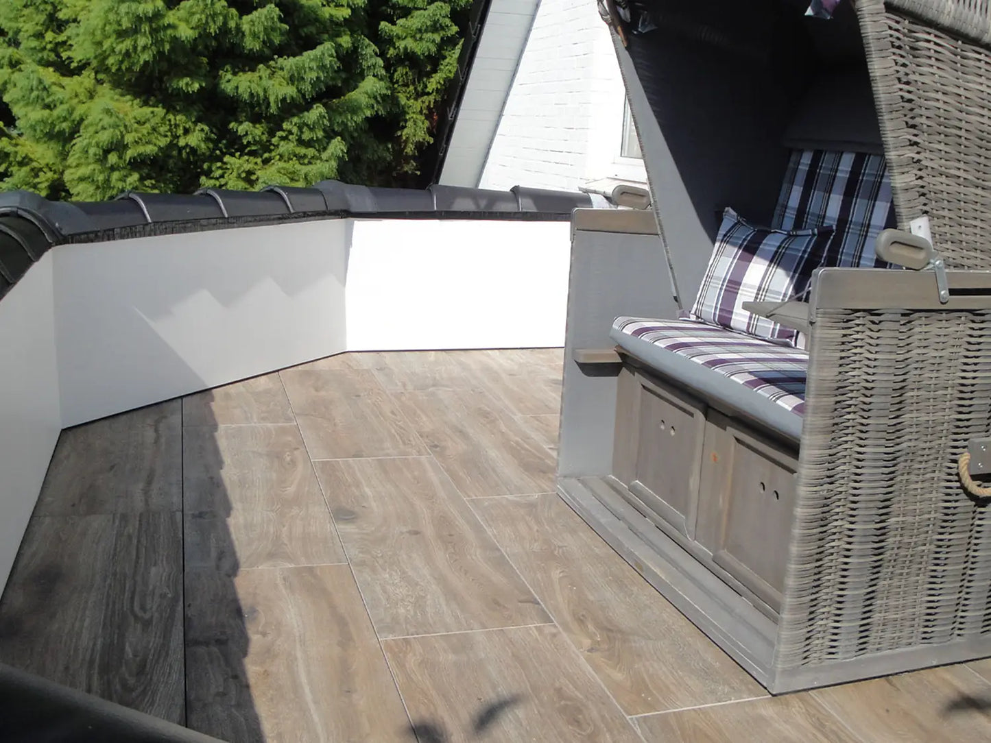 120x40 CeramicLine²-Terrassenplatten in brauner Holzoptik von Woehe & Heydemann verlegt auf einem Balkon mit Strandkorb