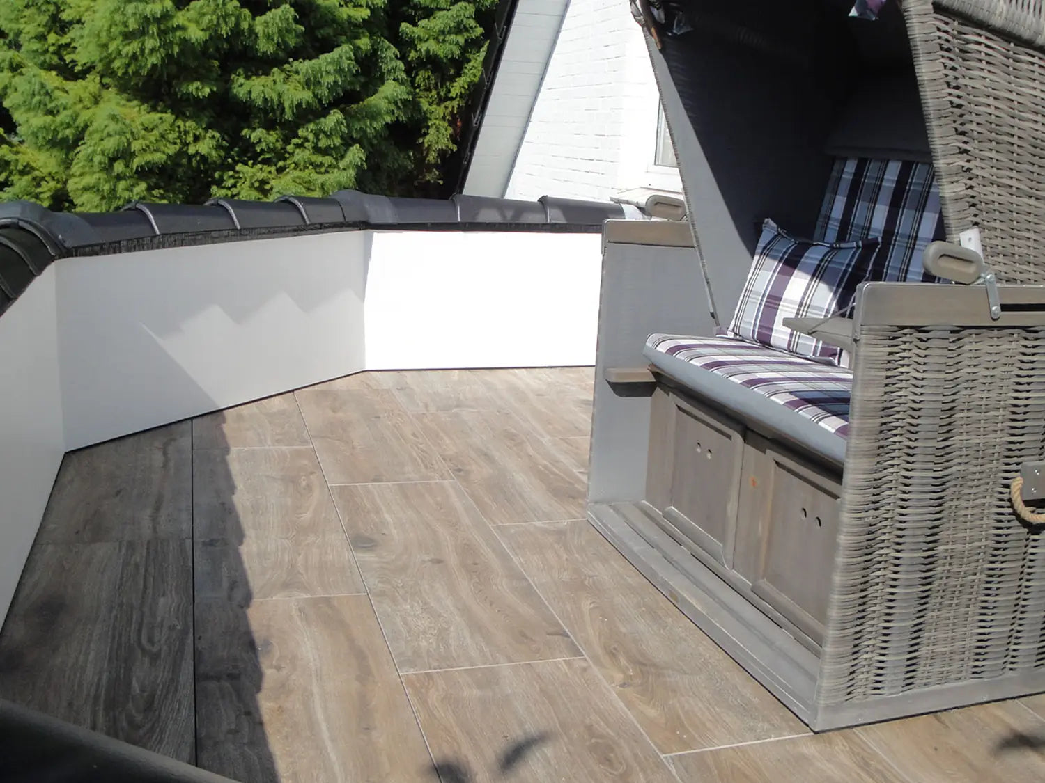 120x40 CeramicLine²-Terrassenplatten in brauner Holzoptik von Woehe & Heydemann verlegt auf einem Balkon mit Strandkorb