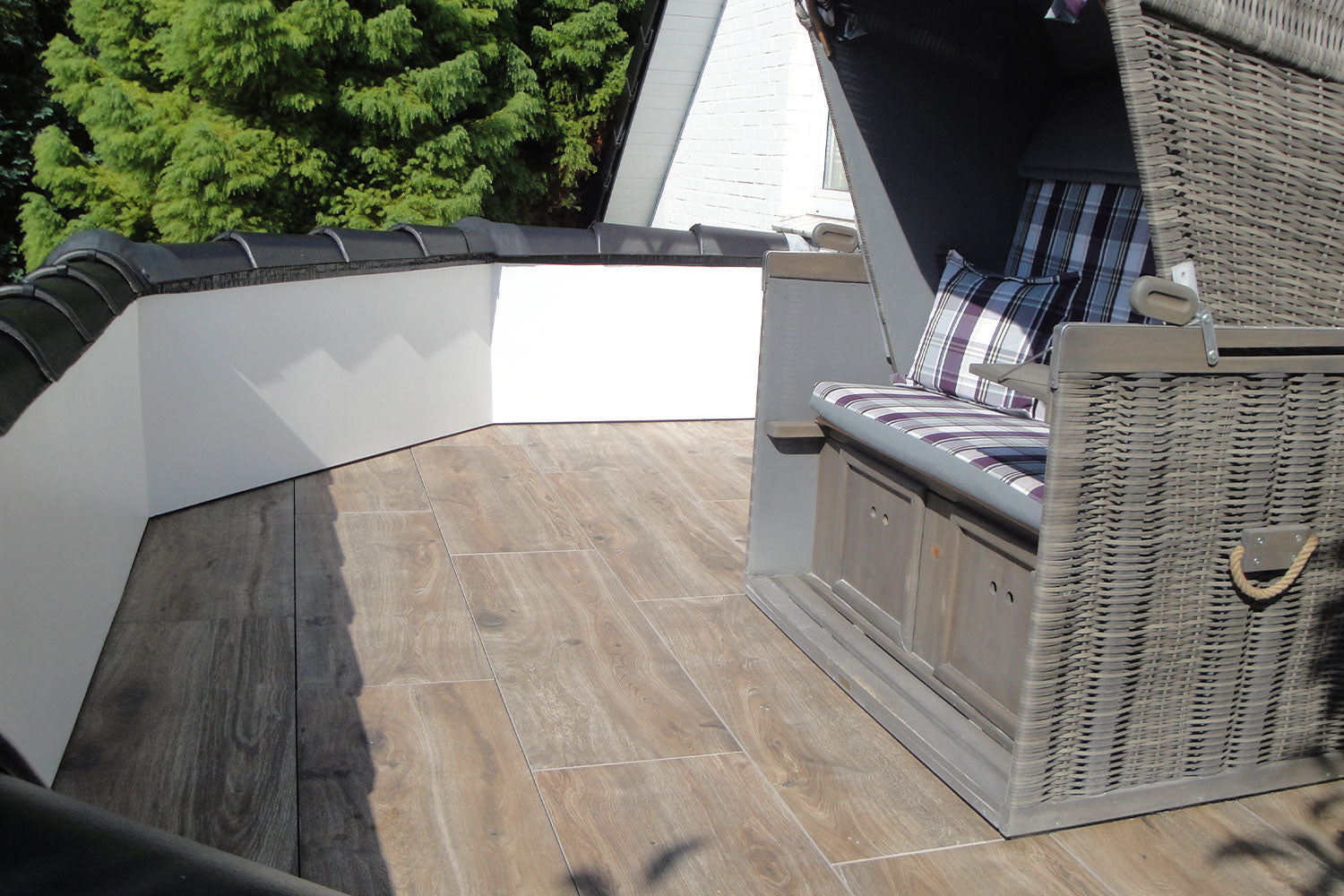 120x40 CeramicLine²-Terrassenplatten in brauner Holzoptik von Woehe & Heydemann verlegt auf einem Balkon mit Strandkorb