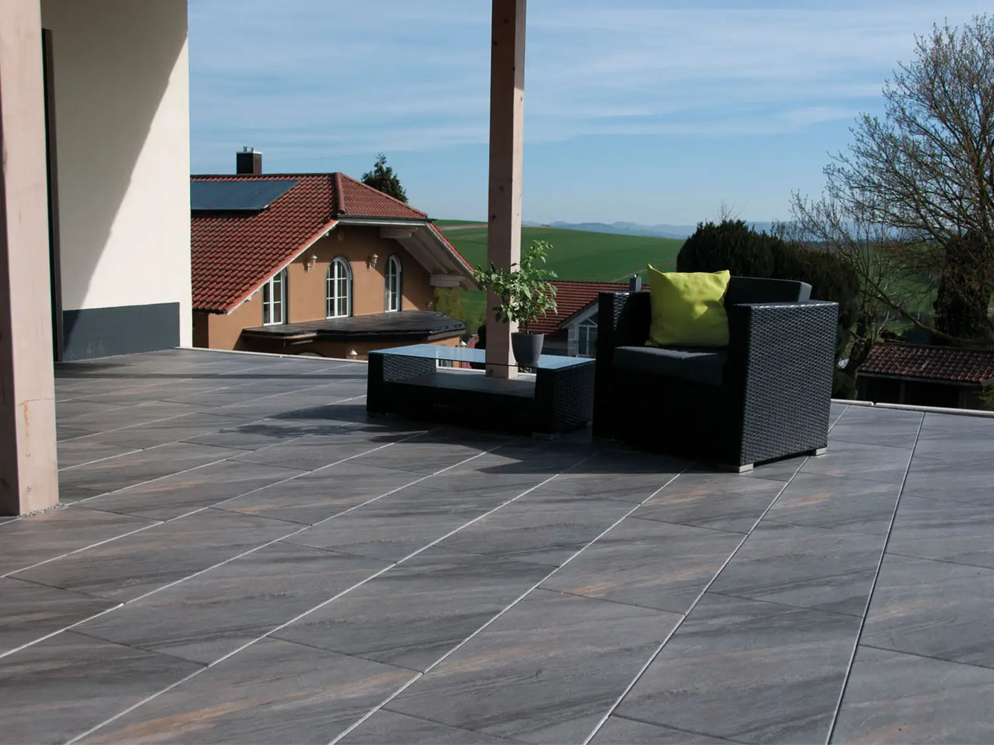 80x40 NanoLine-Terrassenplatten in grauer Natursteinoptik von Woehe & Heydemann verlegt auf einer modernen Terrasse mit Blick auf die Berge