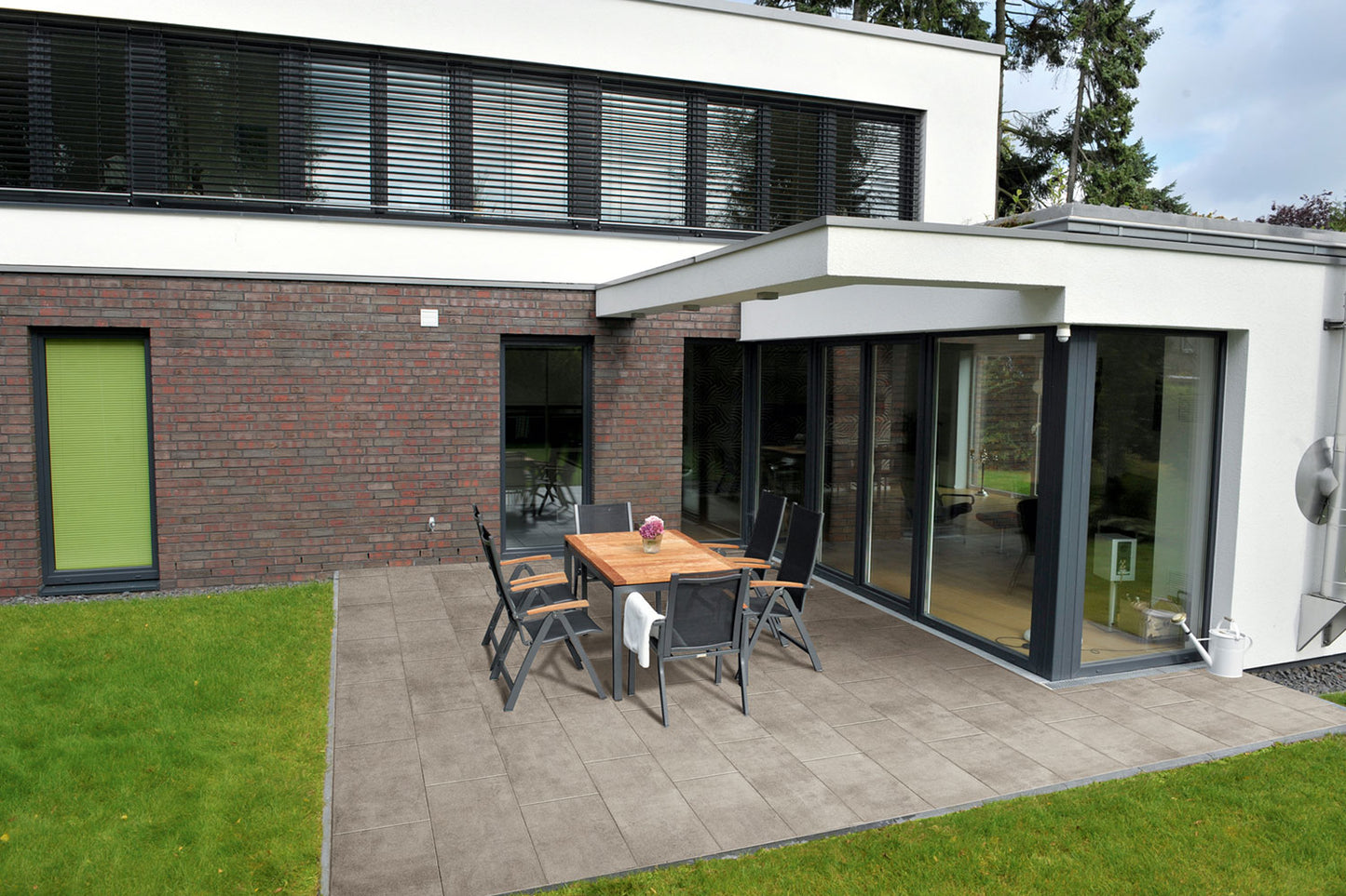 80x40 PremiumLine-Terrassenplatten in beiger Natursteinoptik von Woehe & Heydemann verlegt auf einer modernen Terrasse mit Gartentisch