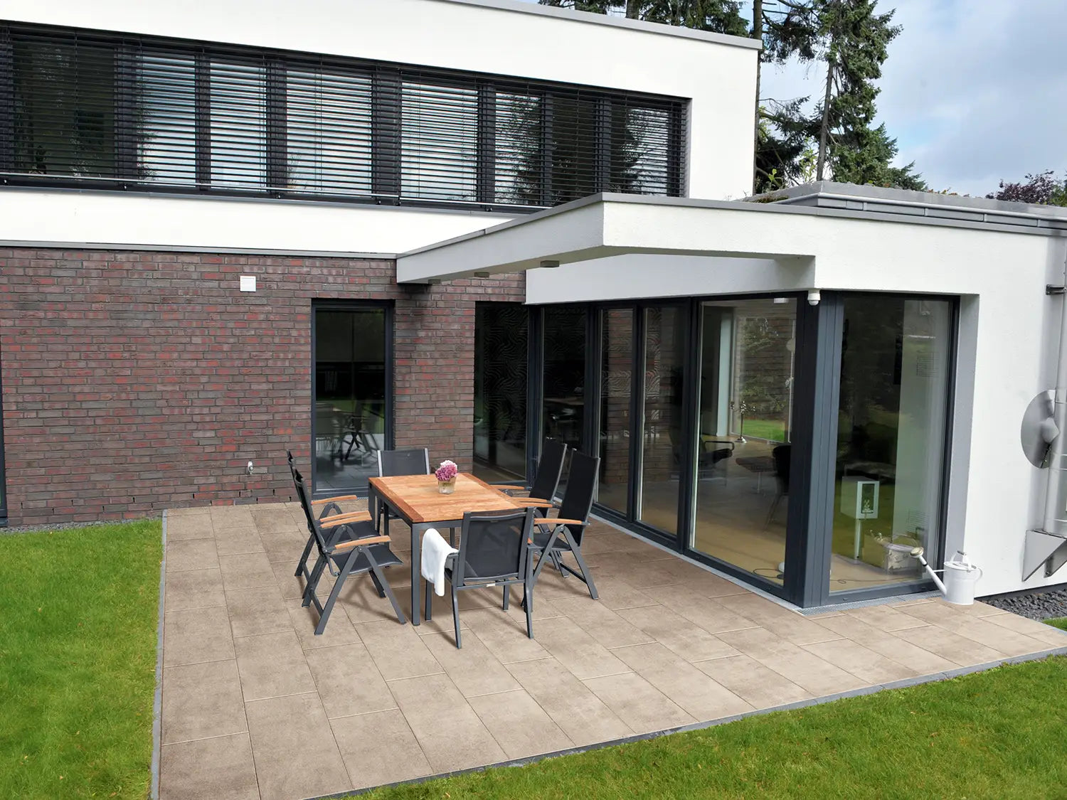 80x40 CreativeLine-Terrassenplatten in beiger Natursteinoptik von Woehe & Heydemann verlegt auf einer modernen Terrasse mit Gartentisch