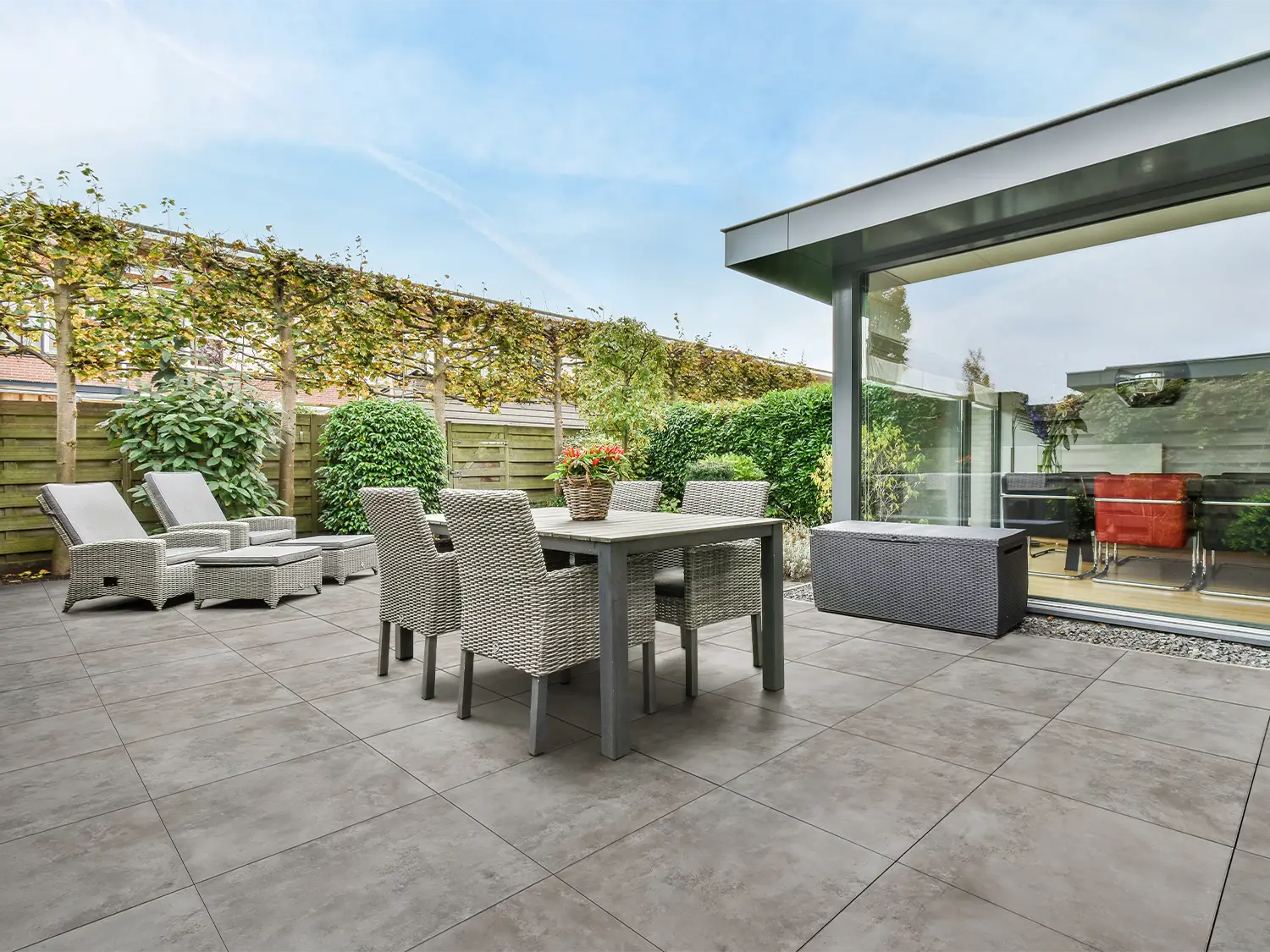 60x60 CreativeLine-Terrassenplatten in beiger Betonoptik von Woehe & Heydemann verlegt auf einer modernen Terrasse mit Esstsich und Liegestühlen