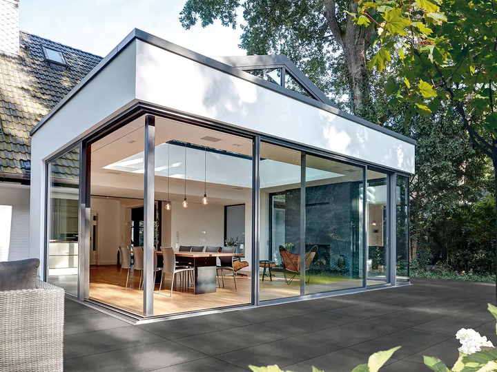 100x50 CreativeLine-Terrassenplatten in grauer Natursteinoptik von Woehe & Heydemann verlegt auf einer modernen Terrasse am Wintergarten