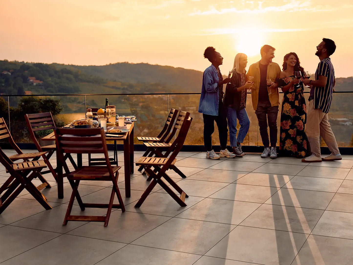 60x60 CreativeLine-Betonplatten in beiger Beton-Optik von Woehe & Heydemann verlegt auf einer modernen Dachterrasse. Menschen die sich unterhalten und gedeckter Tisch.