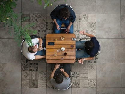 60x60 CreativeLine-Betonplatten in grauer Mosaik-Optik mit farblich passender grauer Beton-Optik von Woehe & Heydemann verlegt auf einer modernen Terrasse mit einem Esstisch und vier Personen