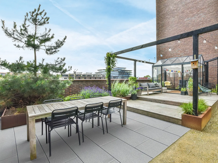 60x40 LuxoGran-Terrassenplatten in grauer Natursteinoptik von Woehe & Heydemann verlegt auf einer modernen Dachterrasse  mit Gewächshaus und Lichterkette