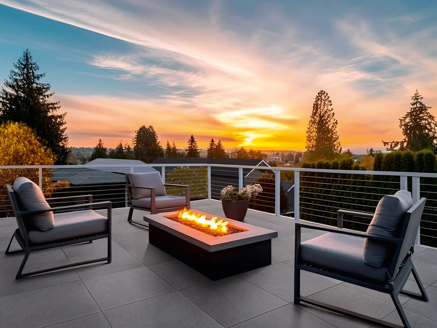 60x60 LuxoGran-Terrassenplatten in schwarzer Natursteinoptik von Woehe & Heydemann verlegt auf einer modernen Dachterrasse mit Feuer und Sonnenuntergang
