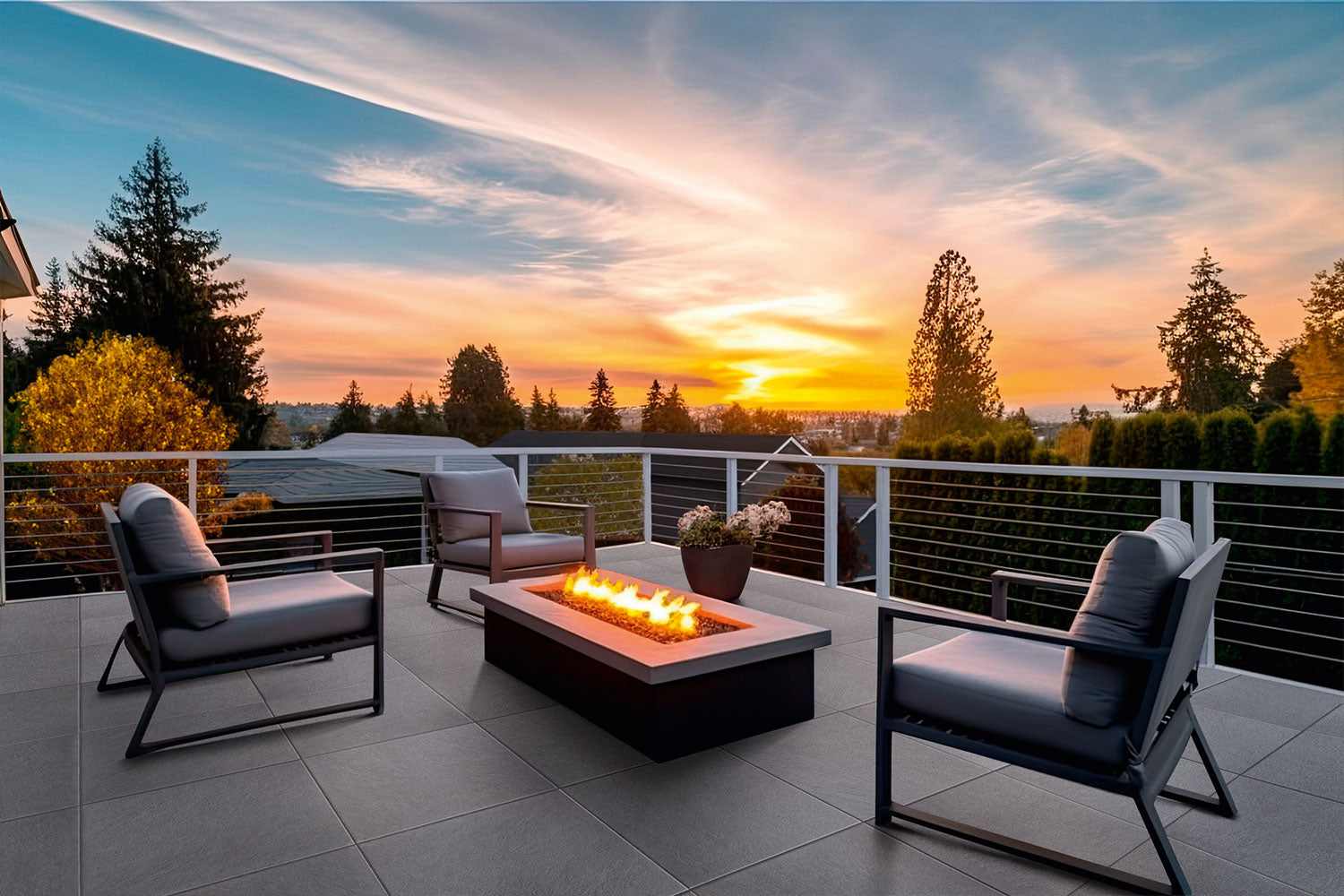 60x60 LuxoGran-Terrassenplatten in grauer Natursteinoptik von Woehe & Heydemann verlegt auf einer modernen Dachterrasse mit Feuer und Sonnenuntergang