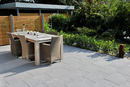 80x40 NanoLine-Terrassenplatten in grauer Natursteinoptik von Woehe & Heydemann verlegt auf einer modernen Terrasse mit Esstisch