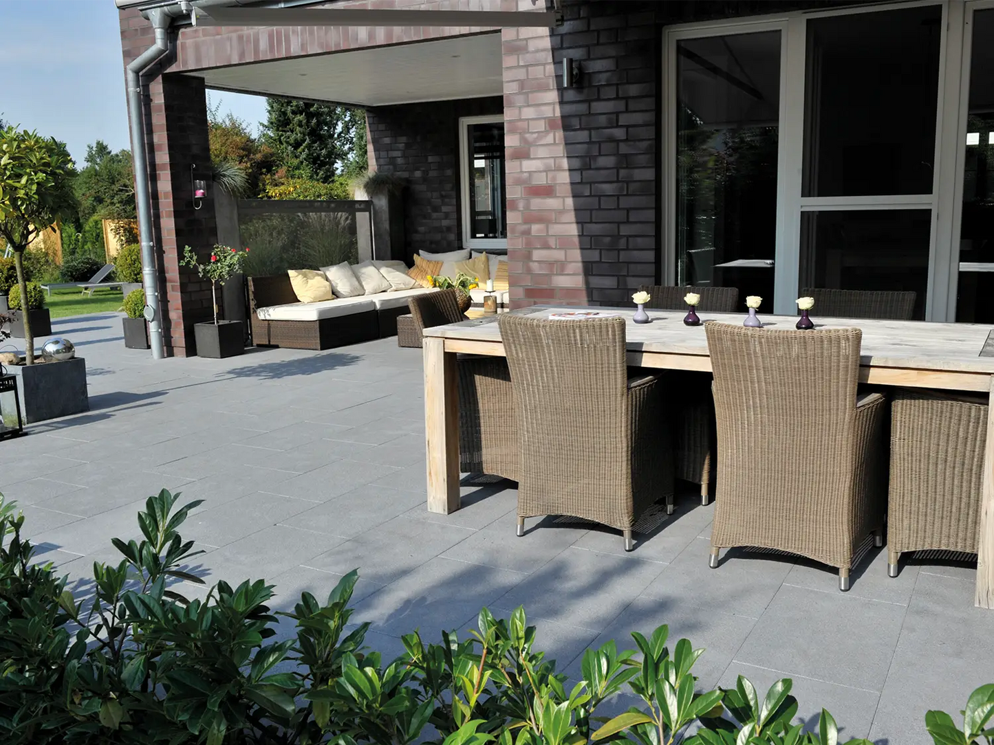 80x40 NanoLine-Terrassenplatten in grauer Natursteinoptik von Woehe & Heydemann verlegt auf einer modernen Terrasse mit Esstisch und Loungeecke