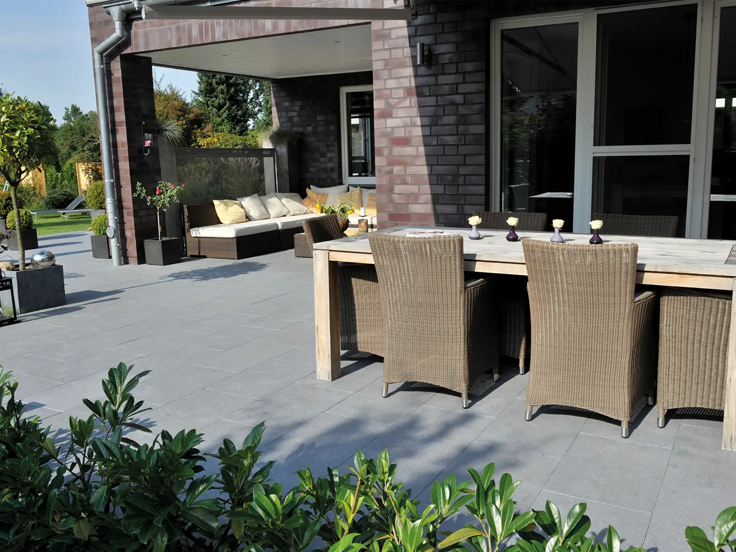 80x40 NanoLine-Terrassenplatten in grauer Natursteinoptik von Woehe & Heydemann verlegt auf einer modernen Terrasse mit Esstisch und Loungeecke