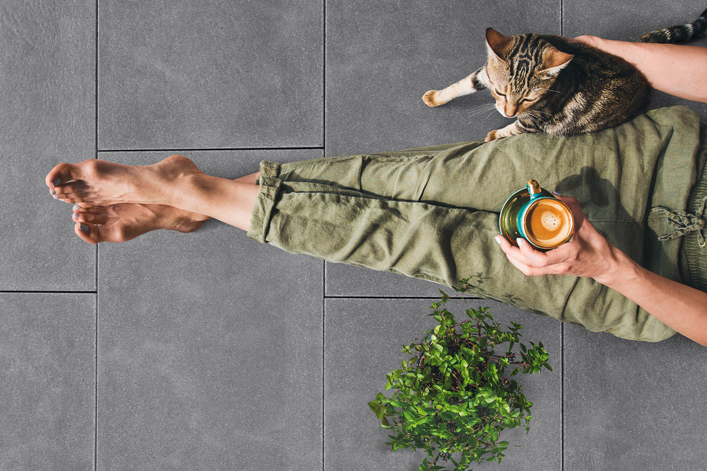 80x40 NanoLine-Terrassenplatten in grauer Natursteinoptik von Woehe & Heydemann verlegt auf einer Terrasse mit Frau mit Katze