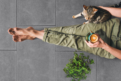 80x40 NanoLine-Terrassenplatten in grauer Natursteinoptik von Woehe & Heydemann verlegt auf einer Terrasse mit Frau mit Katze