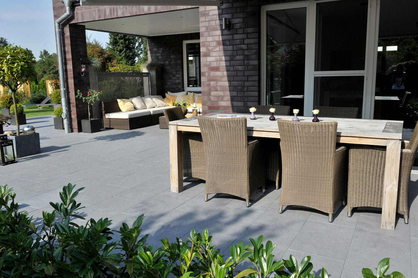 80x40 NanoLine-Terrassenplatten in grauer Natursteinoptik von Woehe & Heydemann verlegt auf einer modernen Terrasse mit Esstisch und Loungemöbeln