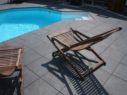 40x40 NanoLine-Terrassenplatten in grauer Natursteinoptik von Woehe & Heydemann verlegt auf einer modernen Terrasse am Pool