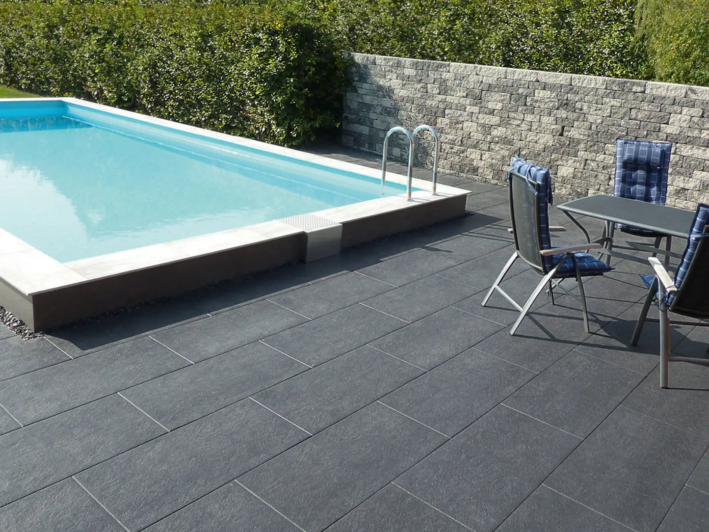 80x40 NanoLine-Terrassenplatten in grauer Natursteinoptik von Woehe & Heydemann verlegt auf einer modernen Terrasse am Pool