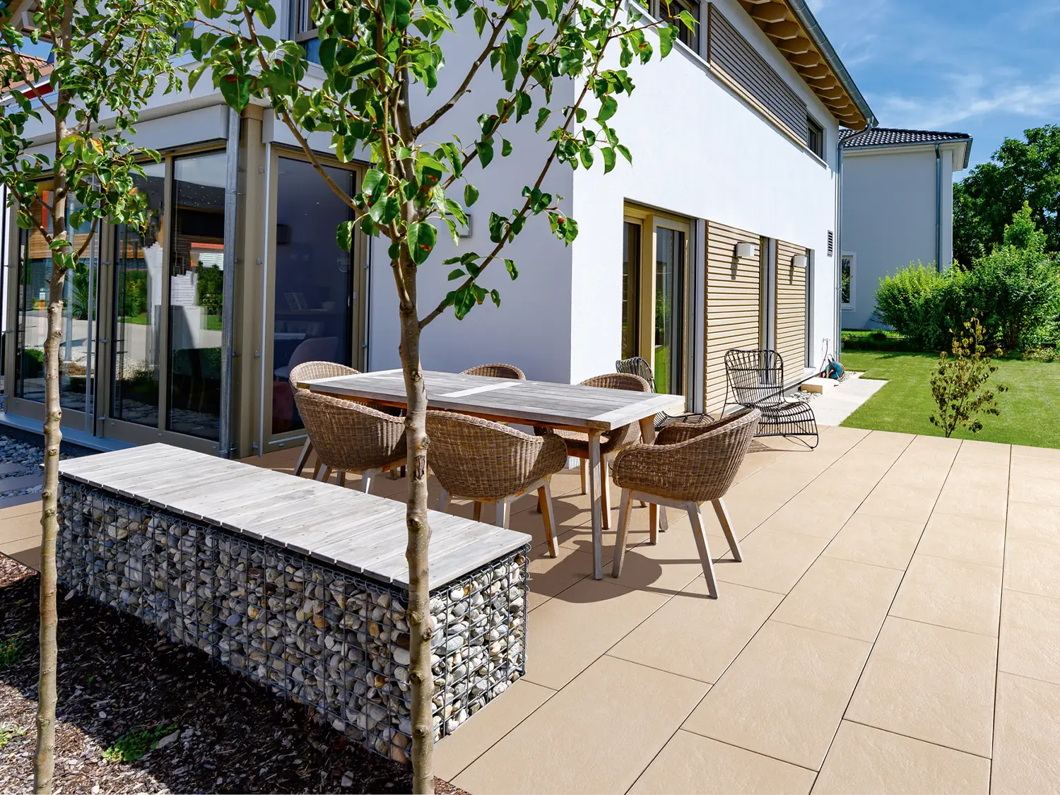 80x40 NanoLine-Terrassenplatten in beiger Natursteinoptik von Woehe & Heydemann verlegt auf einer modernen Terrasse mit Gartentisch am Haus
