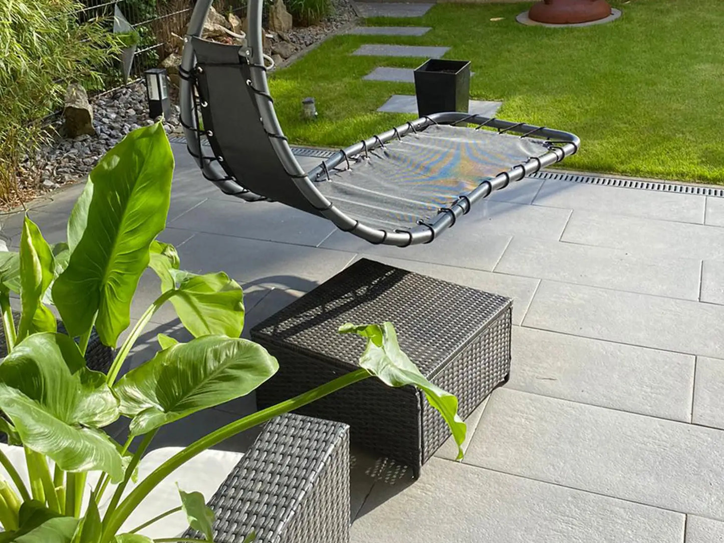 80x40 PremiumLine-Terrassenplatten in grauer Natursteinoptik von Woehe & Heydemann verlegt im Garten mit Liege