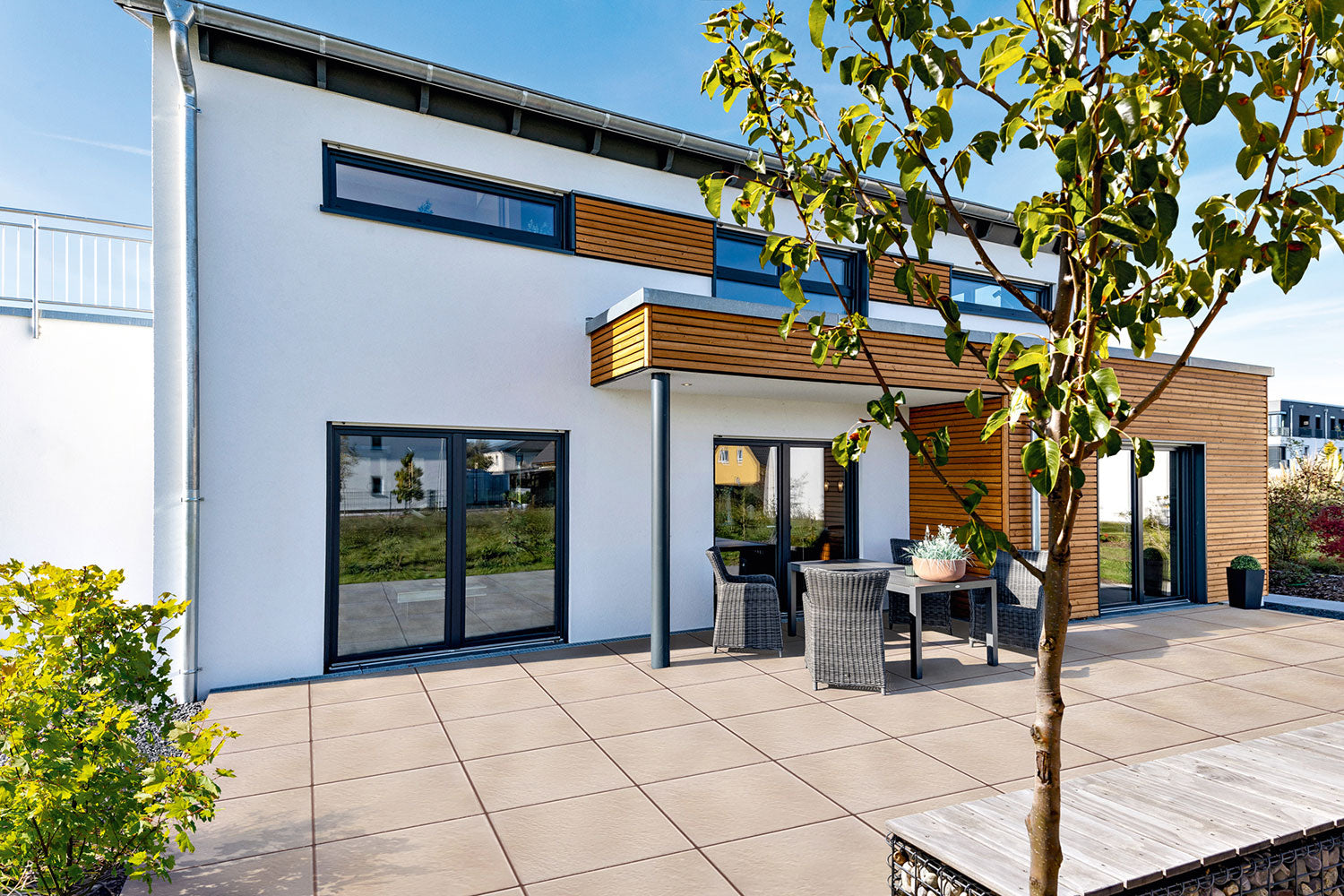 60x60 PremiumLine-Terrassenplatten in beiger Natursteinoptik von Woehe & Heydemann verlegt auf einer modernen Terrasse Gartentisch