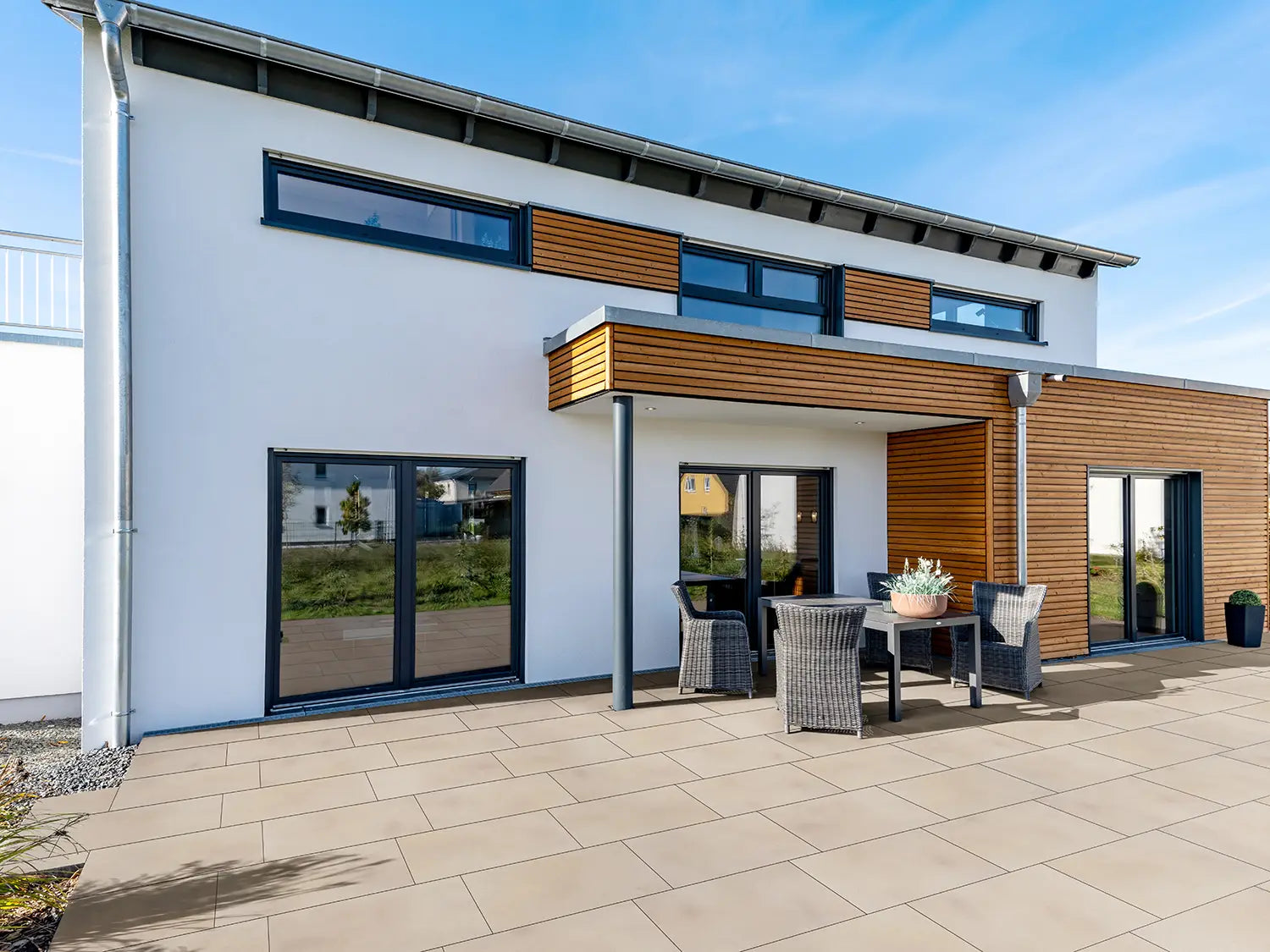 80x40 PremiumLine-Terrassenplatten in beiger Natursteinoptik von Woehe & Heydemann verlegt auf einer modernen Terrasse Gartentisch
