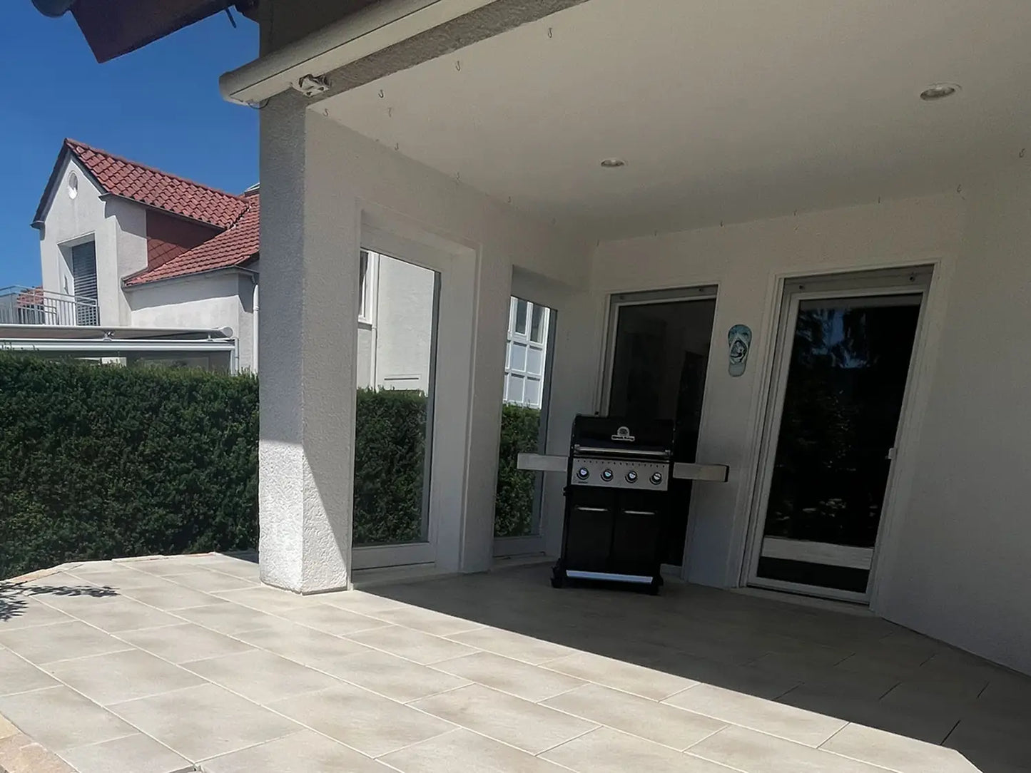 80x40 PremiumLine-Terrassenplatten in beiger Natursteinoptik von Woehe & Heydemann verlegt auf einer modernen Terrasse mit Grill