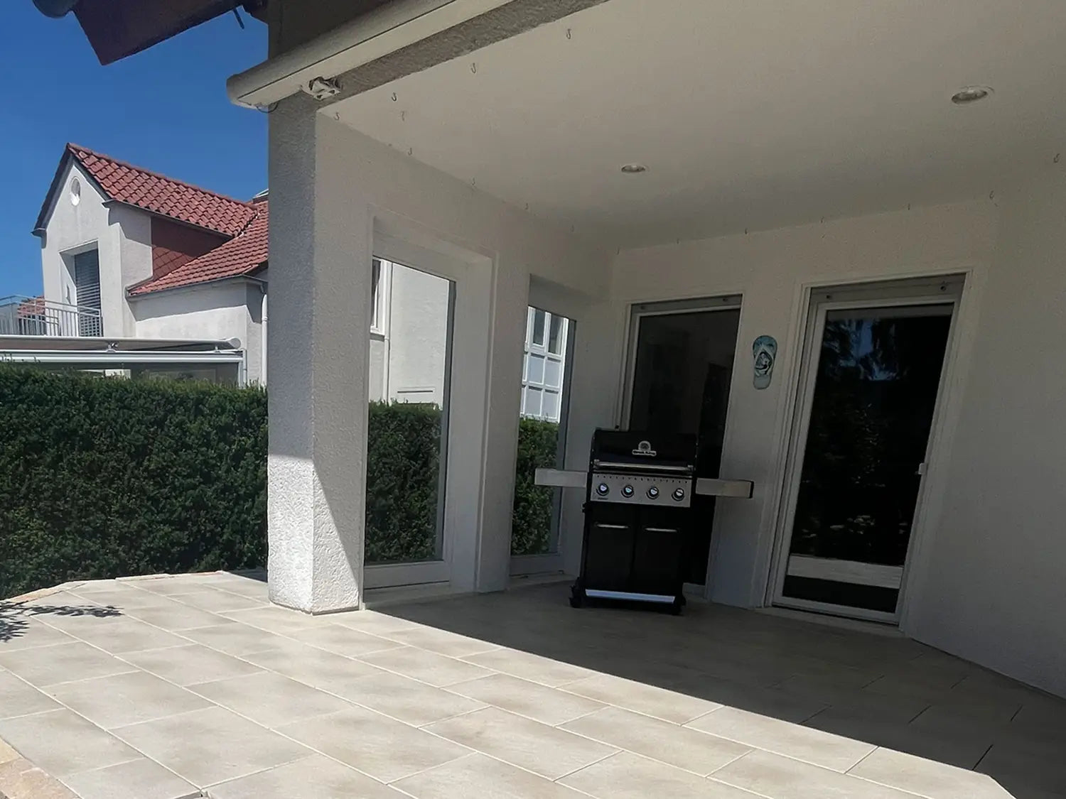 80x40 PremiumLine-Terrassenplatten in beiger Natursteinoptik von Woehe & Heydemann verlegt auf einer modernen Terrasse mit Grill