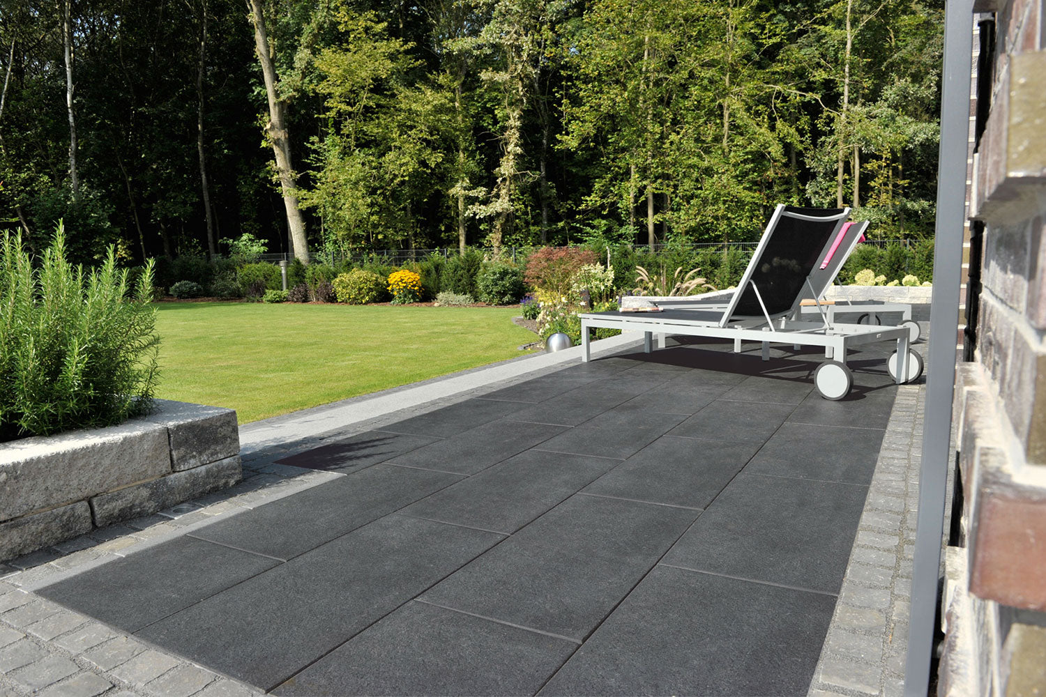 80x40 PremiumLine-Terrassenplatten in grauer Natursteinoptik von Woehe & Heydemann verlegt auf einer modernen Terrasse mit Liegestühlen