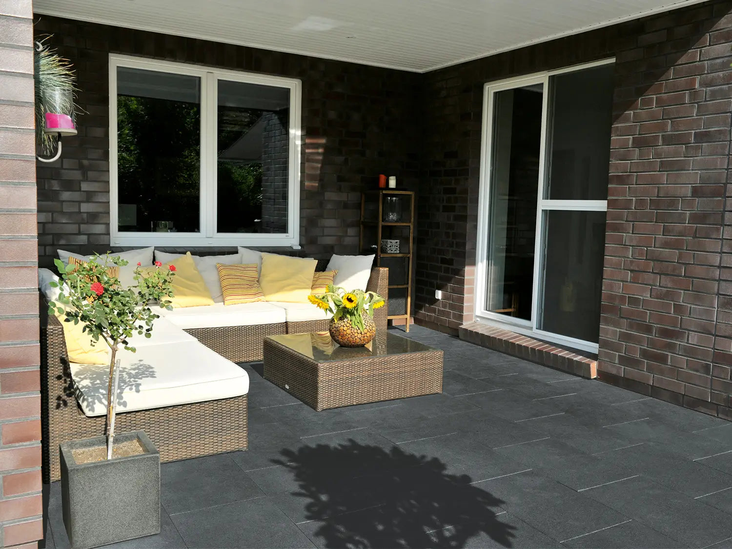 60x40 NanoLine-Terrassenplatten in anthraziter Natursteinoptik von Woehe & Heydemann verlegt auf einer modernen Terrasse mit überdachter Lounge 