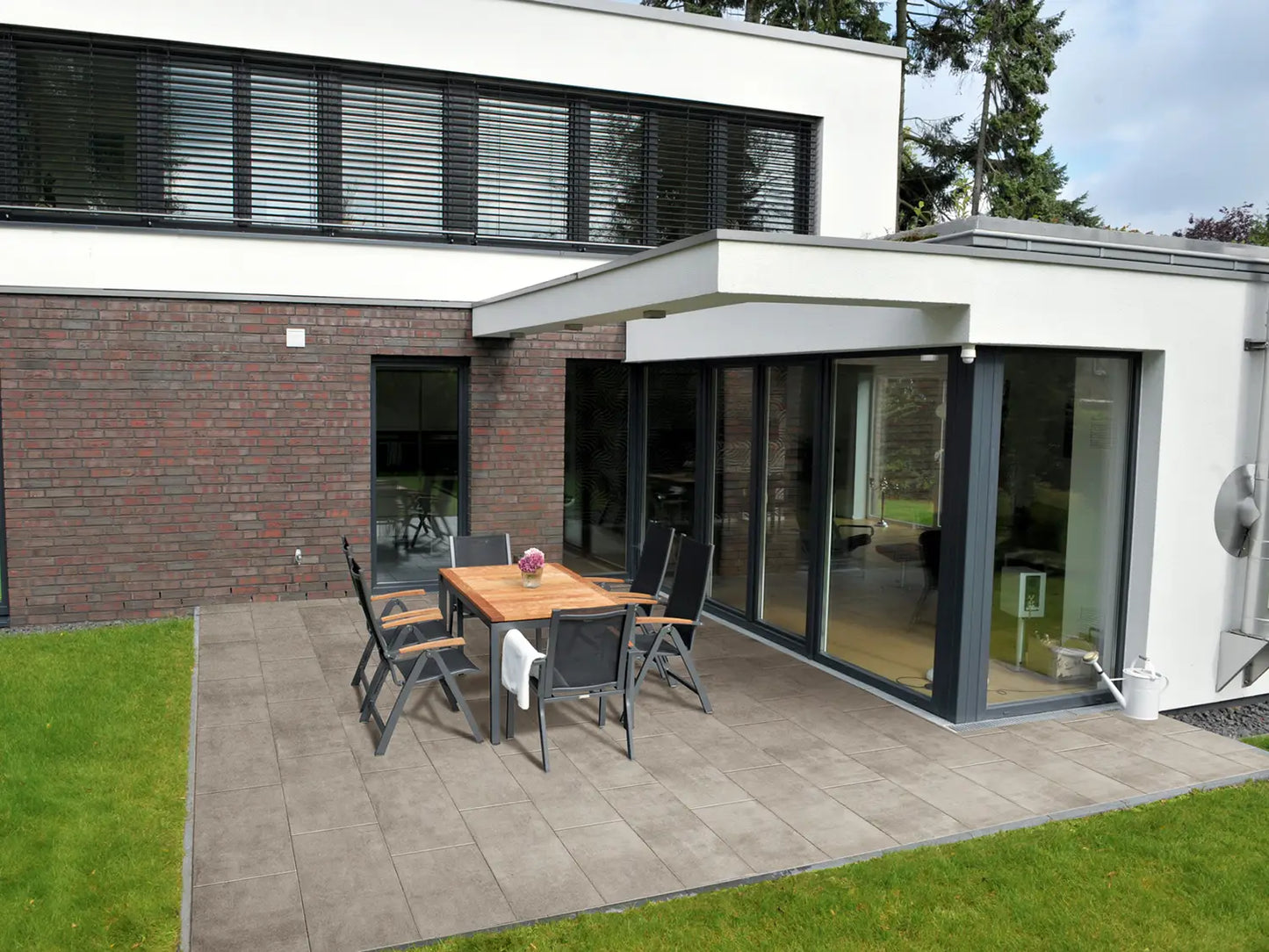 80x40 CreativeLine-Terrassenplatten in beiger Natursteinoptik von Woehe & Heydemann verlegt auf einer modernen Terrasse mit Gartentisch