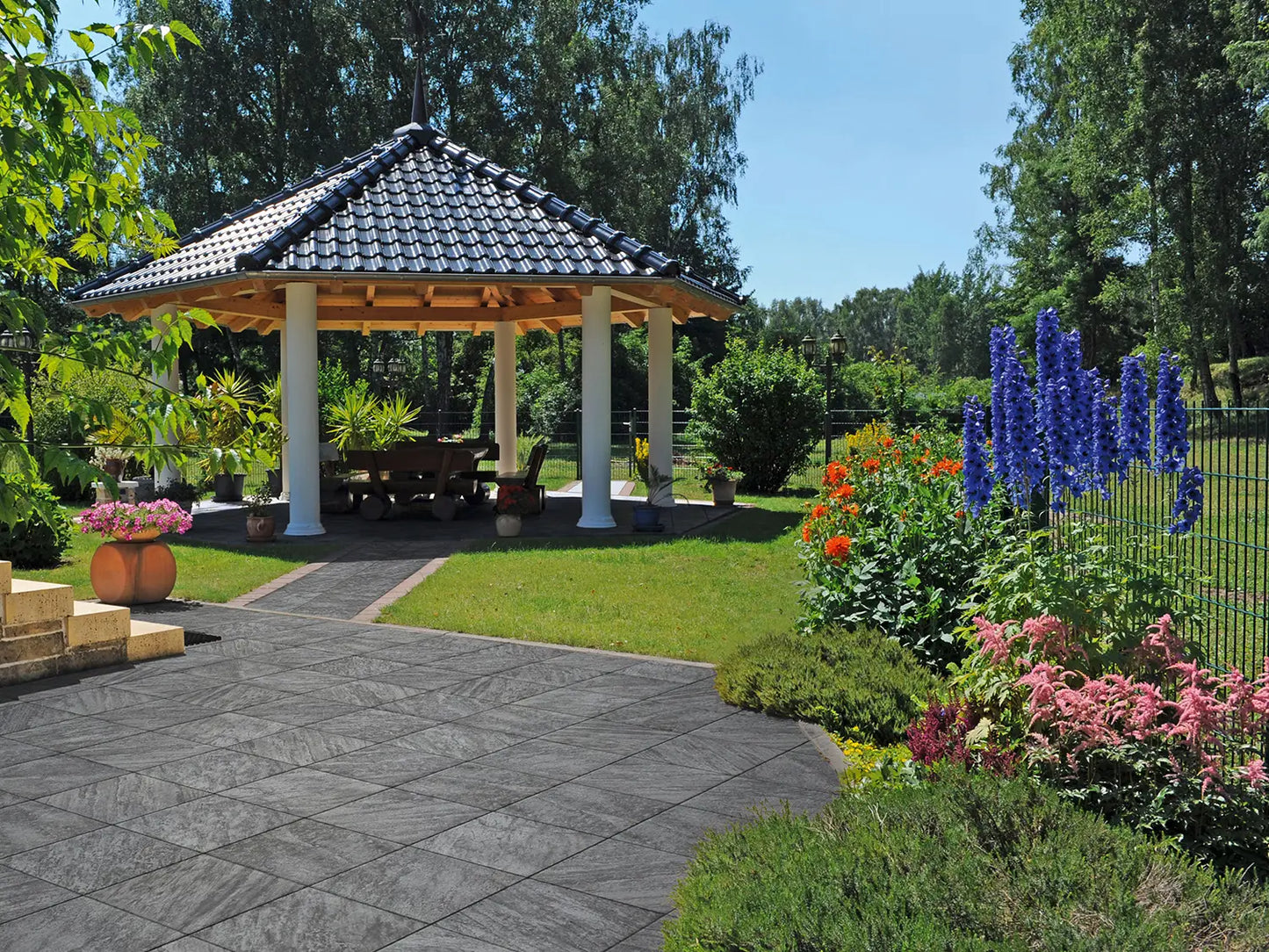 50x50 CreativeLine-Terrassenplatten in grauer Natursteinoptik von Woehe & Heydemann verlegt auf einer modernen Terrasse mit Pavillon und Rasenfläche