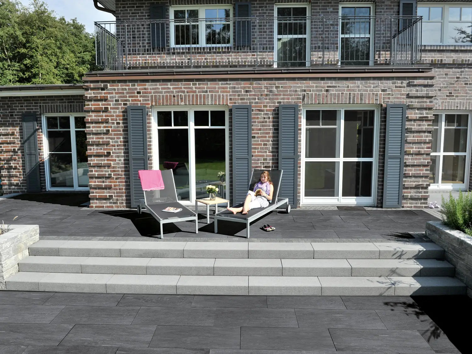 100x50 CeramicLine²-Terrassenplatten in grauer Natursteinoptik von Woehe & Heydemann verlegt auf einer modernen Terrasse mit Liegestühlen