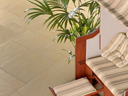 80x40 PremiumLine-Terrassenplatten in beiger Natursteinoptik von Woehe & Heydemann verlegt auf einer modernen Terrasse mit Strandkorb