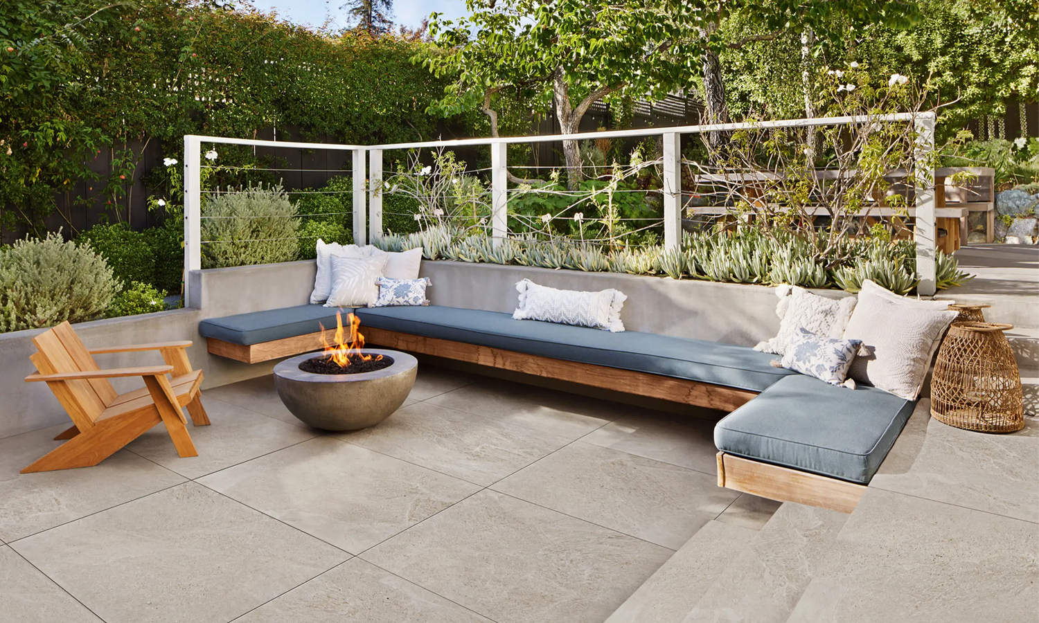 100x100 CeramicLine²-Terrassenplatten in beiger Natursteinoptik von Woehe & Heydemann verlegt auf einer modernen Terrasse mit Feuerstelle