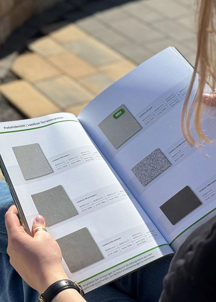 Person blättert durch den Terassenplatten-Katalog von Woehe & Heydemann 